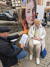 Zeichner malt ein Portrait auf dem Herbstmarkt